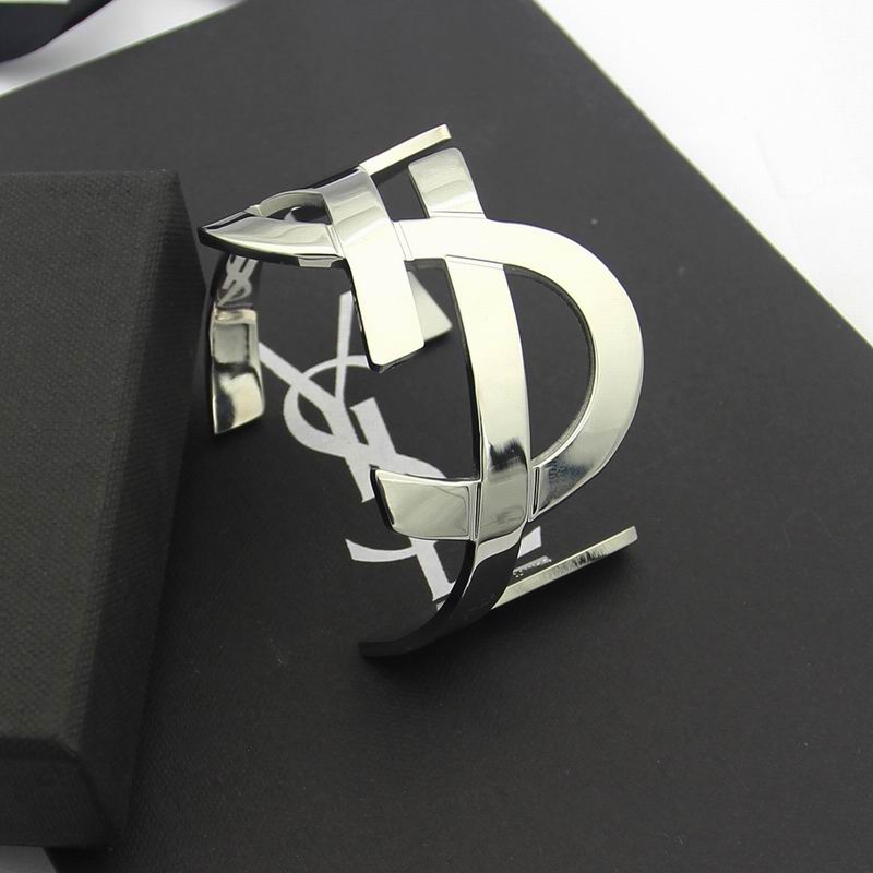 Saint Laurent YSL Monogram Cuff Bracelet in silver-tone polished brass, displayed on a black box