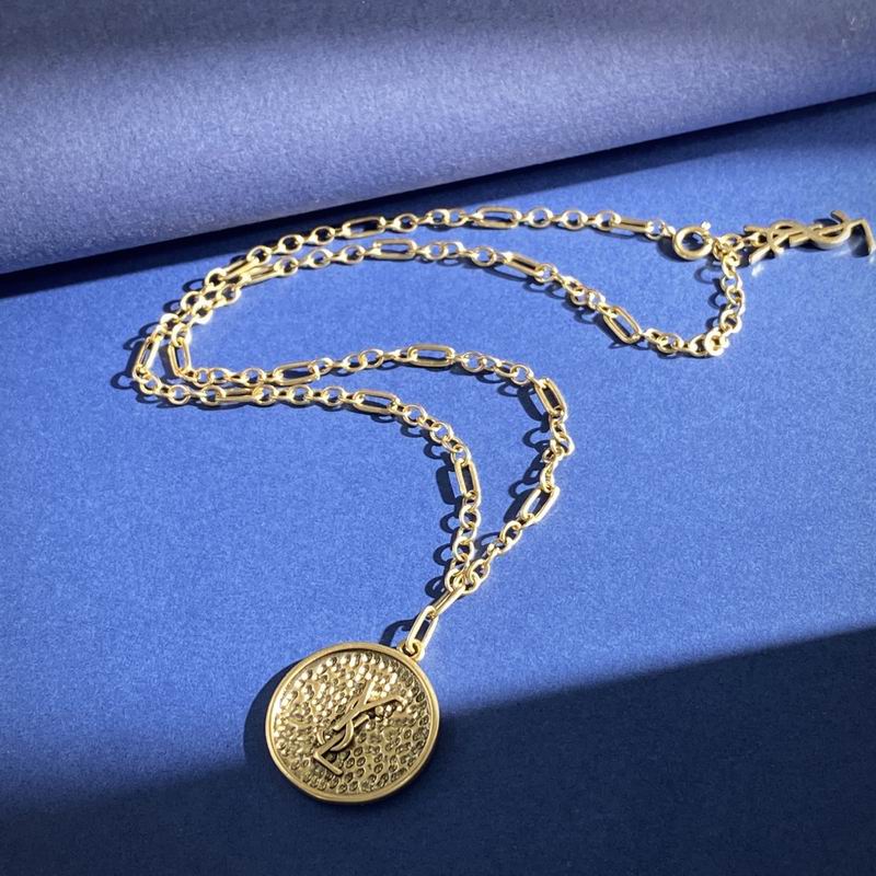 Saint Laurent YSL gold-tone coin pendant necklace on blue background, showing mixed Figaro chain and engraved YSL monogram medallion